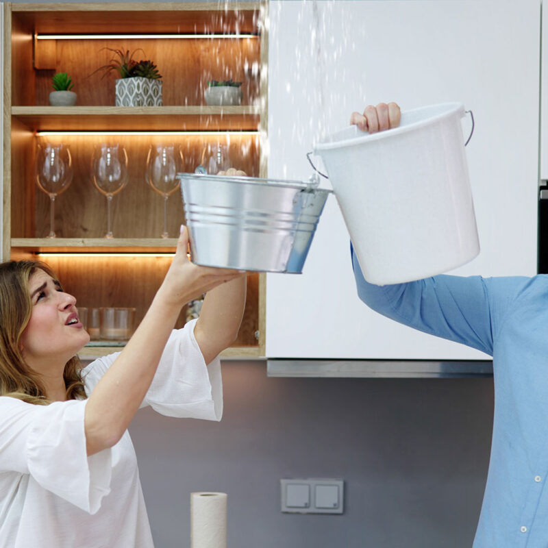 couple holding buckets to catch water coming from water leak in ceiling