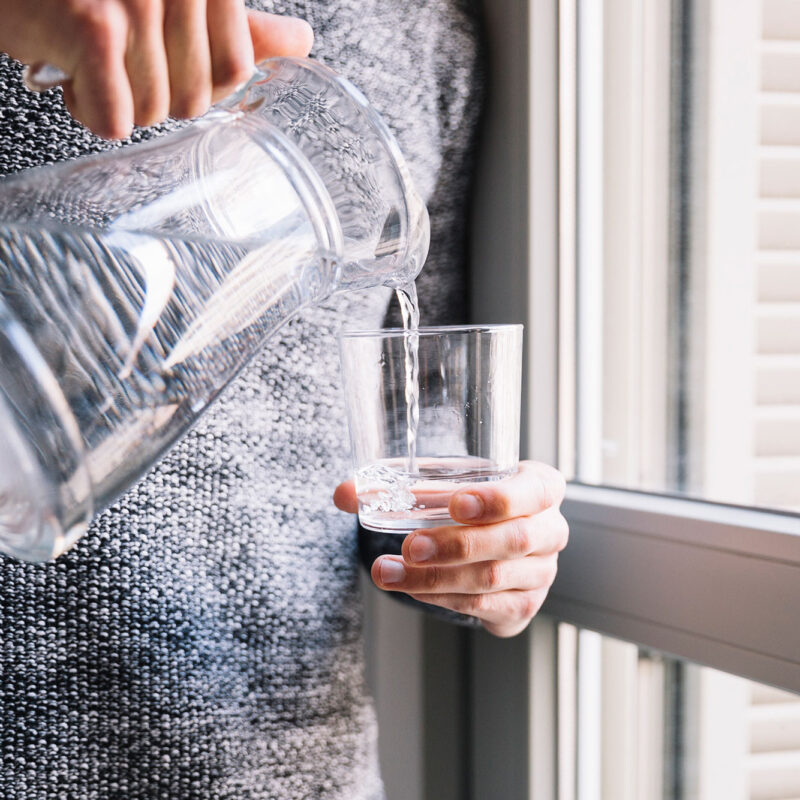 Cropped man pouring water into cup